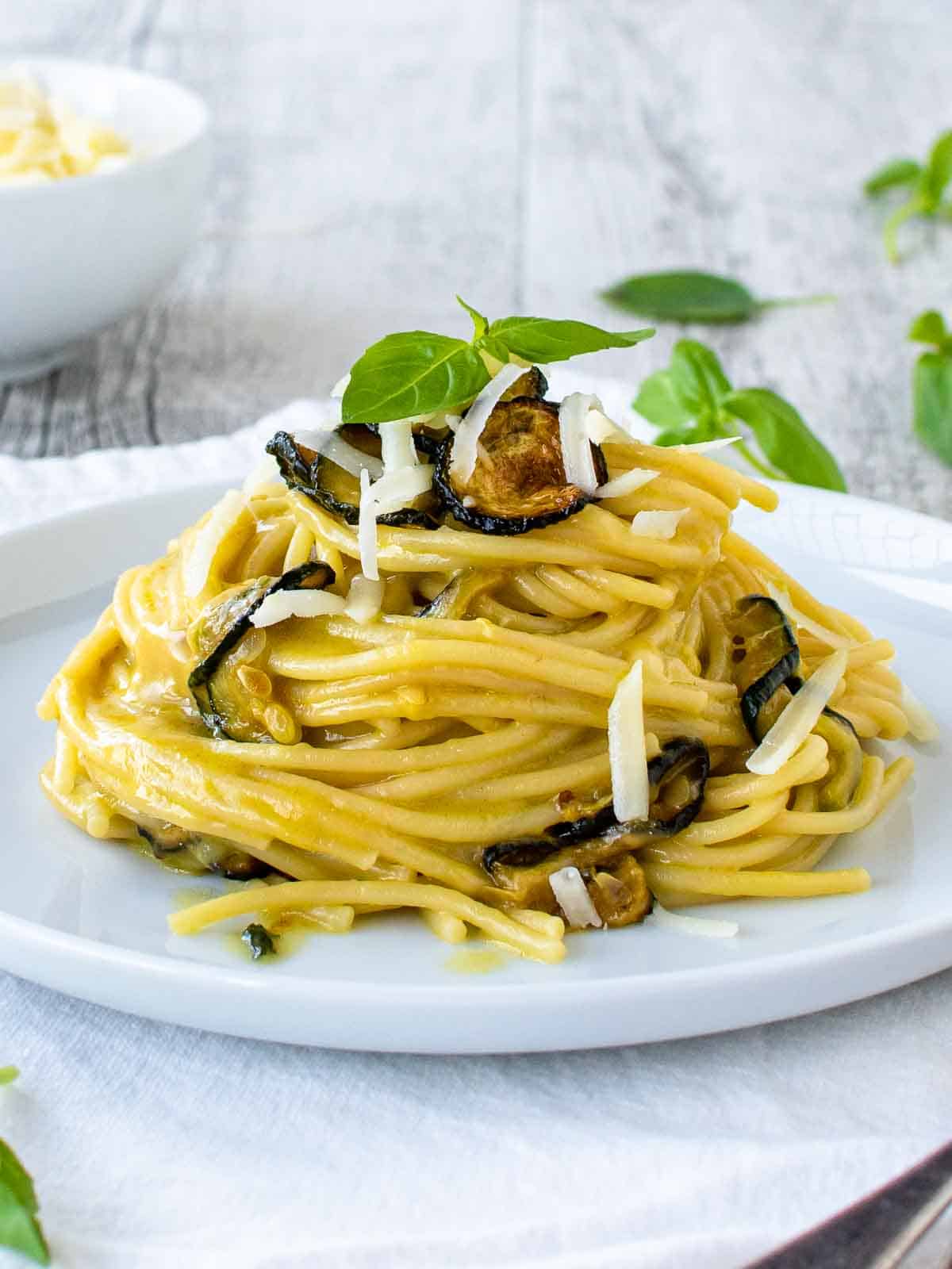 Spaghetti dish with zucchini and basil on a white plate