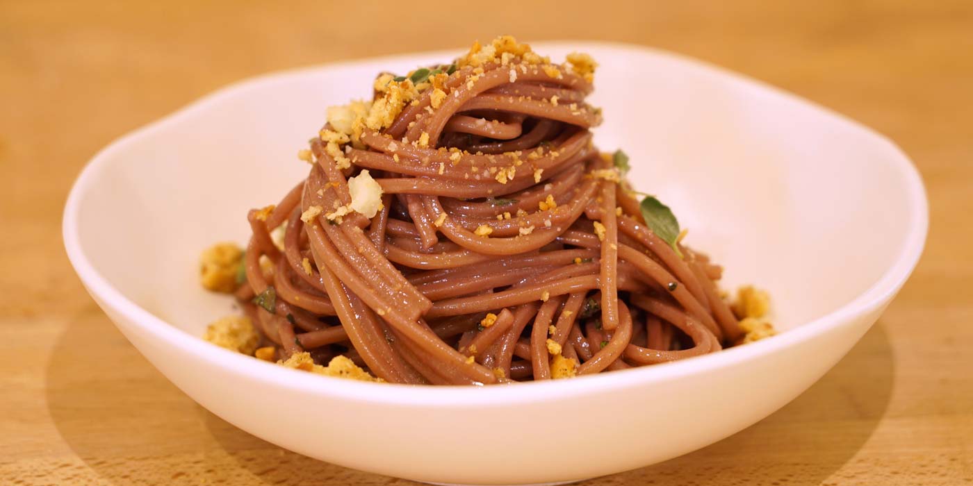 Noodles with garnishes in a white bowl on a wooden surface