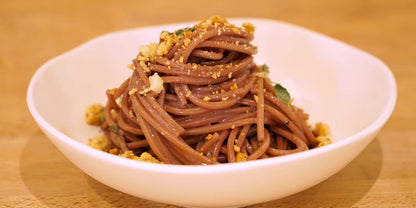 Noodles with garnishes in a white bowl on a wooden surface